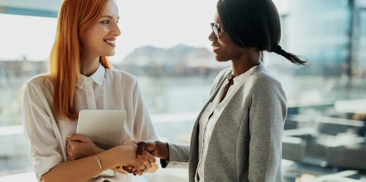 Two businesswomen shaking hands and making eye contact.